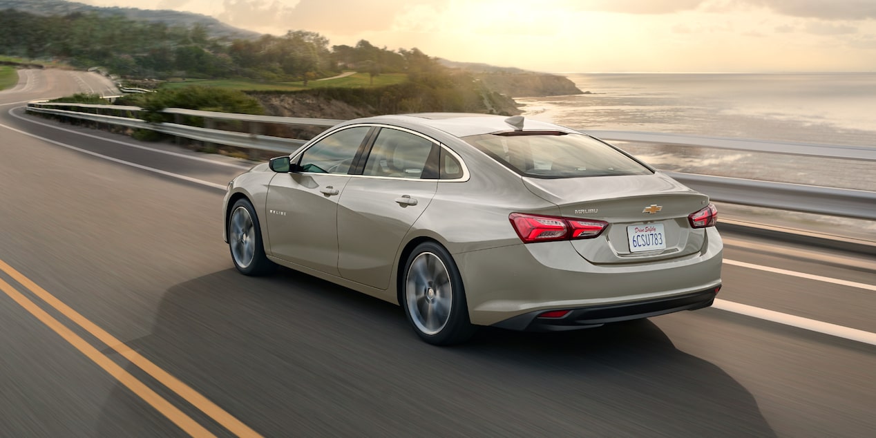 Rear View of a Mineral Grey 2025 Chevy Malibu Driving Next to a Seashore