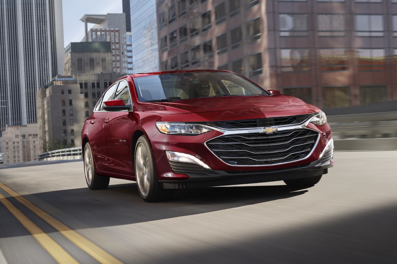 Front Low View of a Red Chevy Malibu Driving Through the City