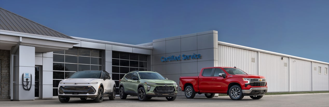 Three Chevrolet Vehicles Parked in Front of a Chevy Certified Service Garage