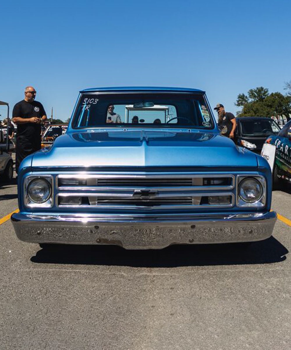 Front View of a Blue Vintage Chevy Pickup Truck in Excellent Condition with a Man Standing Near the Bed