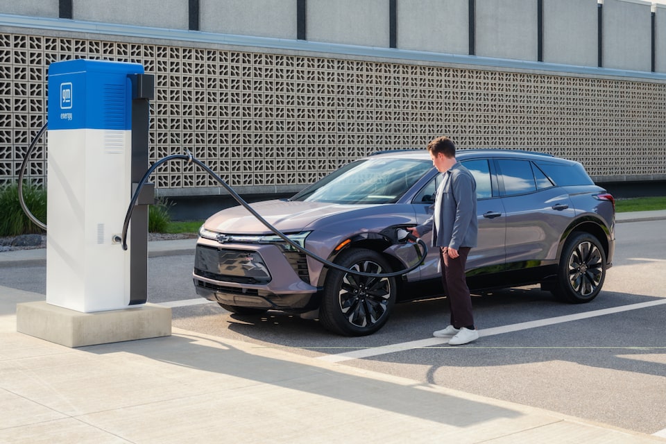 A Man Charging a 2025 Chevrlet EV at an Outdoor Charging Station