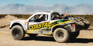 Rear Three-Quarters View of Jake Velasco's Off-Roading Truck Driving in the Desert With Mountains in the Background