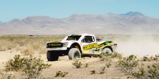 Front Three-Quarters View of Jake Velasco's Off-Roading Truck Driving in the Desert With Mountains in the Background