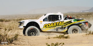 Side View of Jake Velasco's Off-Roading Truck Driving in the Desert With Mountains in the Background