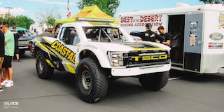 Front Three-Quarters View of Jake Velasco's Off-Roading Truck Parked Near A Couple Tents and RVs