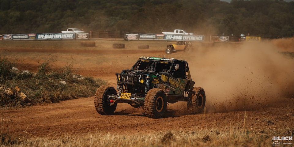 Three Quarters View of an Off-Road Vehicle Driving through the Desert Leaving behind Dust Clouds