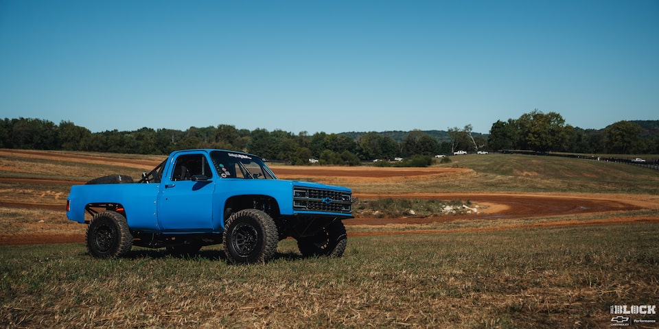 Three Quarters View of a Blue Chevy Pickup Truck on a Grassy Plain under a Clear Blue Sky