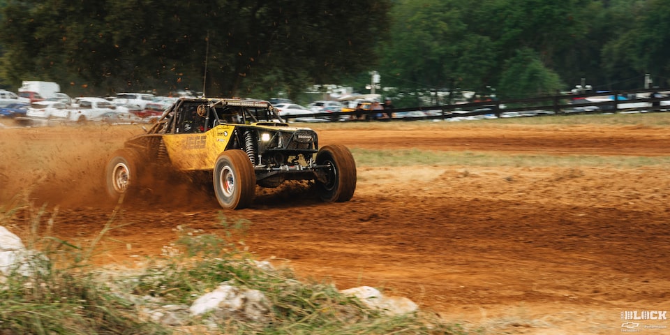 Three Quarters Rear View of an Off-Road Vehicle Speeding with Dust Flying in Front